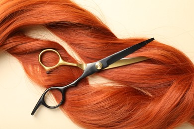 Photo of Hair locks and scissors on beige background, flat lay