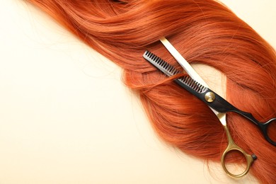 Photo of Hair locks and scissors on beige background, flat lay. Space for text