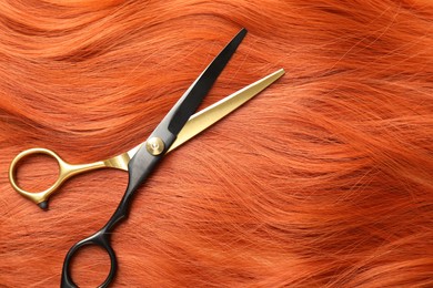 Photo of Scissors on hair lock, top view. Space for text