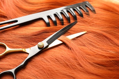 Photo of Scissors and comb on hair lock, closeup