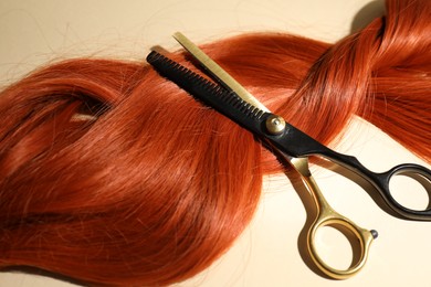 Photo of Hair locks and scissors on beige background, above view