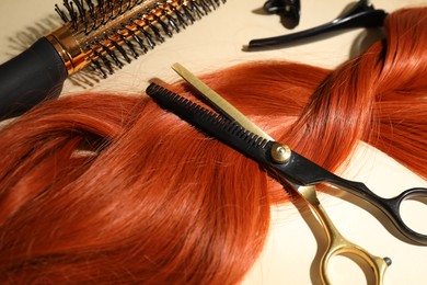 Photo of Hair locks and different hairdresser's tools on beige background, closeup