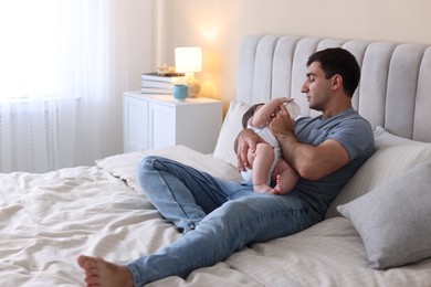 Photo of Father feeding his little baby with bottle on bed at home. Space for text