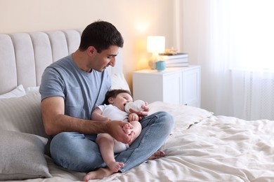 Photo of Father feeding his little baby with bottle on bed at home. Space for text