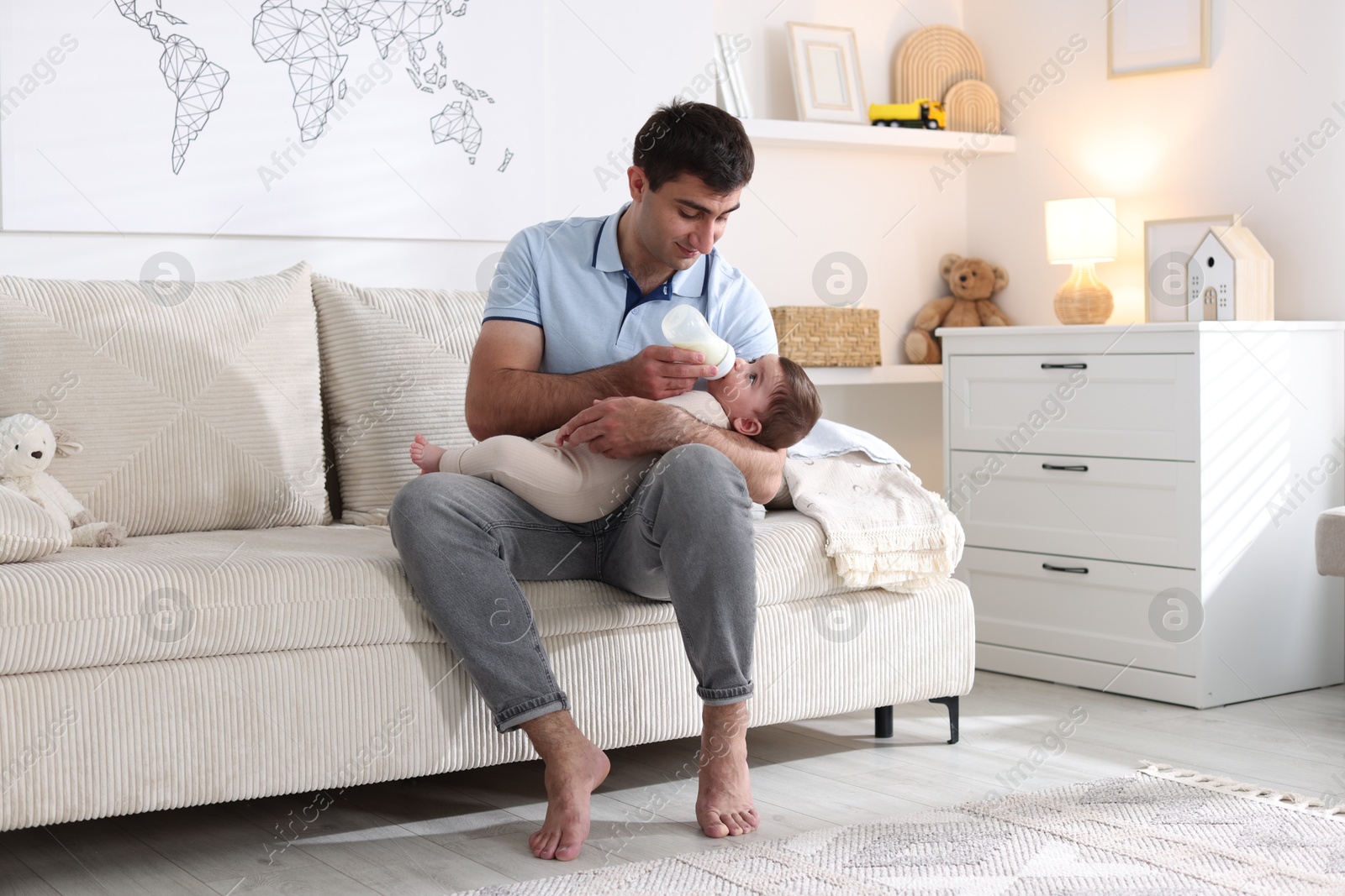 Father feeding his little baby with bottle on sofa at home Photo of Father feeding his little baby with bottle on sofa at home