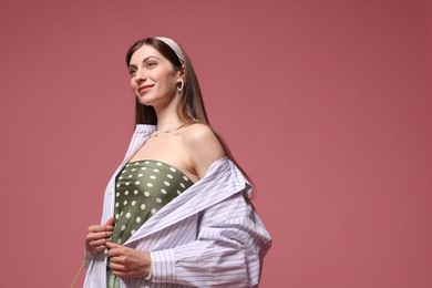 Photo of Fashionable portrait of beautiful woman in stylish outfit on pink background. Space for text
