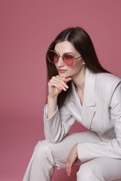 Photo of Fashionable portrait of beautiful woman in stylish outfit on pink background