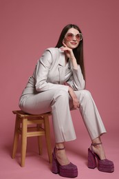 Photo of Fashionable portrait of beautiful woman in stylish outfit on pink background