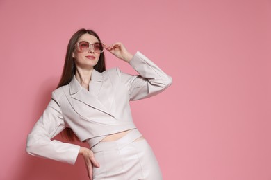 Photo of Fashionable portrait of beautiful woman in stylish outfit on pink background. Space for text