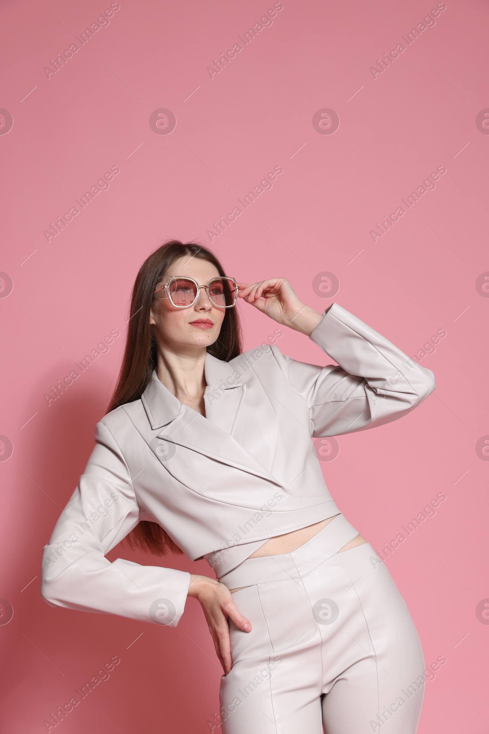 Fashionable portrait of beautiful woman in stylish outfit on pink background Photo of Fashionable portrait of beautiful woman in stylish outfit on pink background