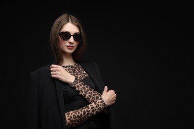 Photo of Fashionable portrait of beautiful woman in stylish outfit on black background. Space for text