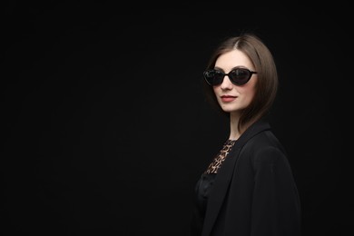 Photo of Fashionable portrait of beautiful woman in stylish outfit on black background. Space for text