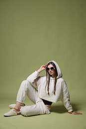 Photo of Fashionable portrait of beautiful woman in stylish outfit on green background
