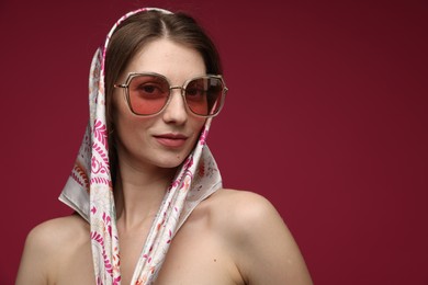 Photo of Fashionable portrait of beautiful woman in stylish outfit on dark red background. Space for text