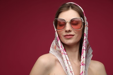 Photo of Fashionable portrait of beautiful woman in stylish outfit on dark red background. Space for text