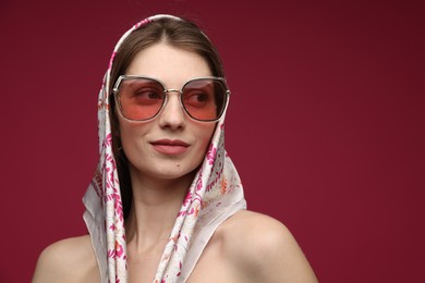 Photo of Fashionable portrait of beautiful woman in stylish outfit on dark red background. Space for text