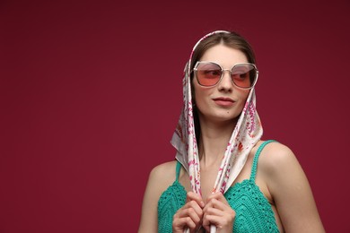 Photo of Fashionable portrait of beautiful woman in stylish outfit on dark red background. Space for text