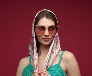 Photo of Fashionable portrait of beautiful woman in stylish outfit on dark red background