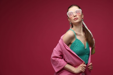Photo of Fashionable portrait of beautiful woman in stylish outfit on dark red background. Space for text