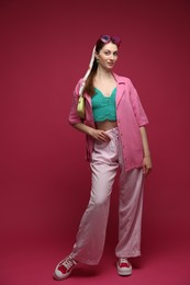 Photo of Fashionable full-length portrait of beautiful woman in stylish outfit on dark red background