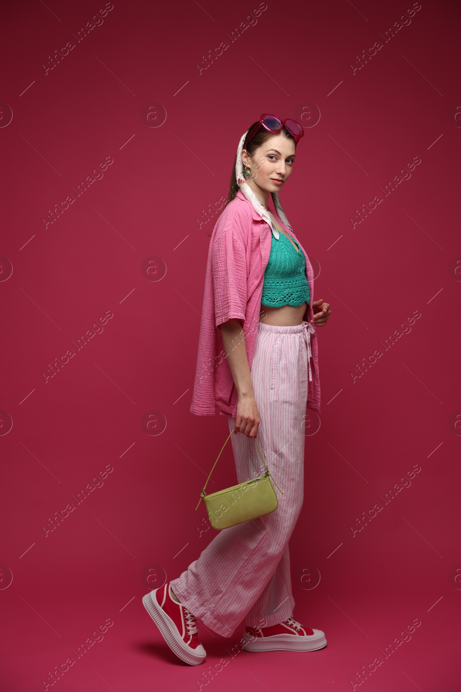Fashionable full-length portrait of beautiful woman in stylish outfit on dark red background Photo of Fashionable full-length portrait of beautiful woman in stylish outfit on dark red background