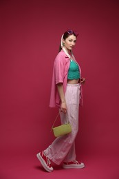 Photo of Fashionable full-length portrait of beautiful woman in stylish outfit on dark red background