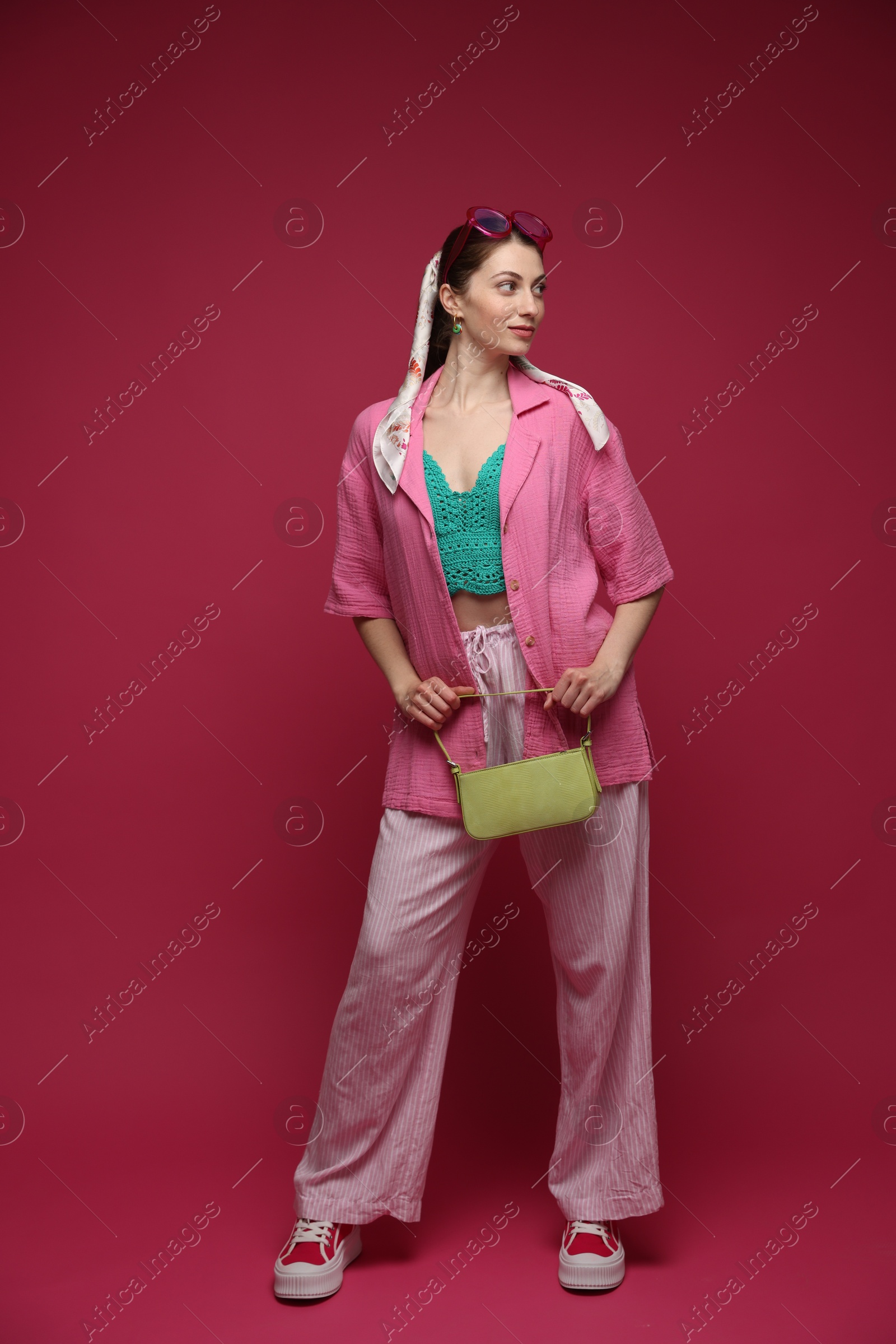 Fashionable full-length portrait of beautiful woman in stylish outfit on dark red background Photo of Fashionable full-length portrait of beautiful woman in stylish outfit on dark red background