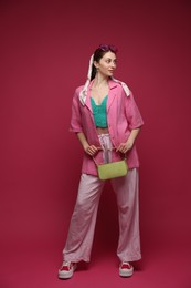 Photo of Fashionable full-length portrait of beautiful woman in stylish outfit on dark red background