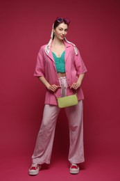 Photo of Fashionable full-length portrait of beautiful woman in stylish outfit on dark red background