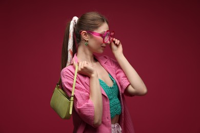 Photo of Fashionable portrait of beautiful woman in stylish outfit on dark red background