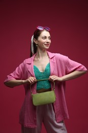 Photo of Fashionable portrait of beautiful woman in stylish outfit on dark red background