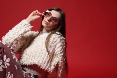 Photo of Fashionable portrait of beautiful woman in stylish outfit on red background. Space for text