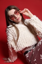 Photo of Fashionable portrait of beautiful woman in stylish outfit on red background