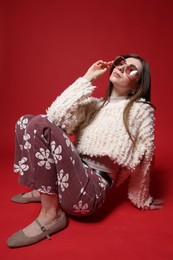 Photo of Fashionable portrait of beautiful woman in stylish outfit on red background