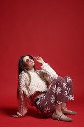 Photo of Fashionable portrait of beautiful woman in stylish outfit on red background. Space for text