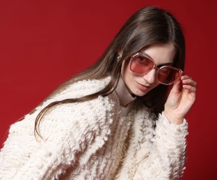 Photo of Fashionable portrait of beautiful woman in stylish outfit on red background