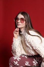 Photo of Fashionable portrait of beautiful woman in stylish outfit on red background