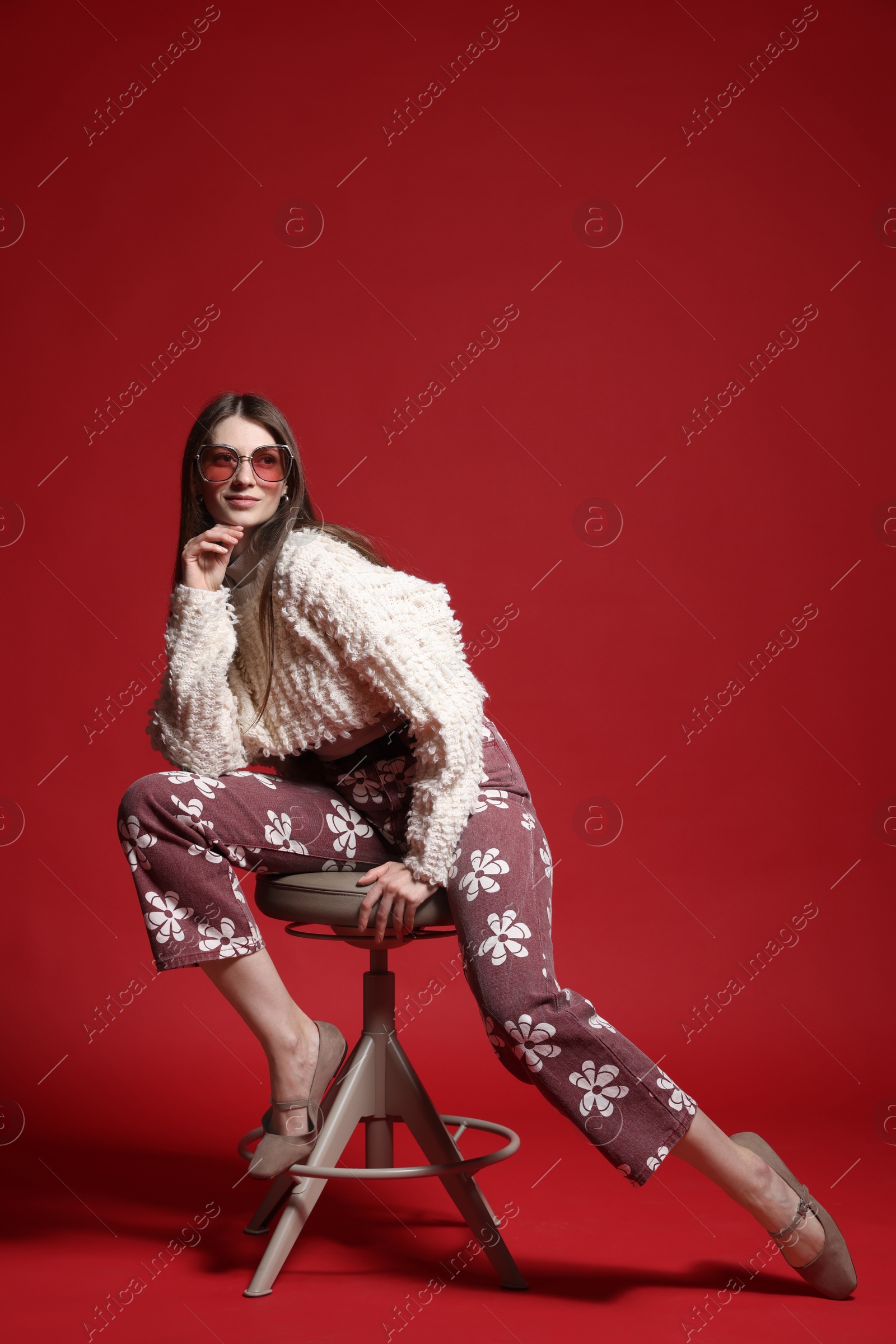 Fashionable portrait of beautiful woman in stylish outfit on red background Photo of Fashionable portrait of beautiful woman in stylish outfit on red background