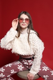 Photo of Fashionable portrait of beautiful woman in stylish outfit on red background