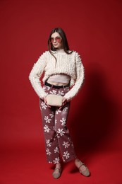 Photo of Fashionable full-length portrait of beautiful woman in stylish outfit on red background