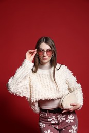 Photo of Fashionable portrait of beautiful woman in stylish outfit on red background