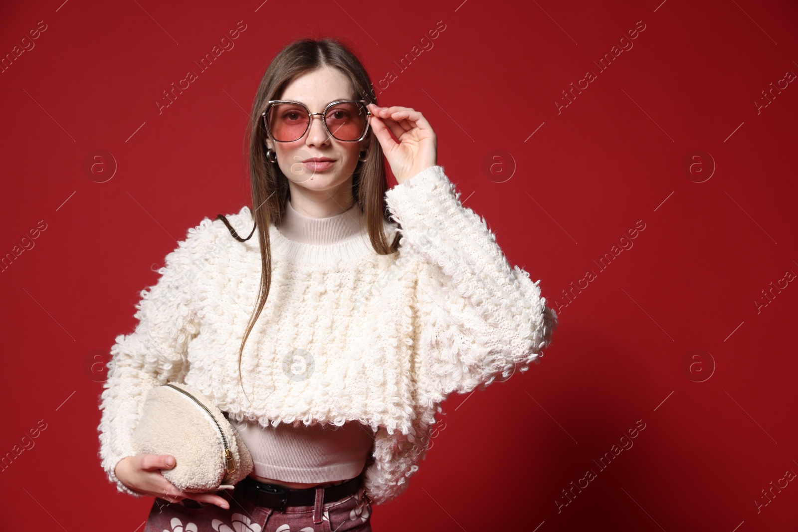 Fashionable portrait of beautiful woman in stylish outfit on red background Photo of Fashionable portrait of beautiful woman in stylish outfit on red background
