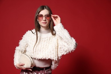 Photo of Fashionable portrait of beautiful woman in stylish outfit on red background