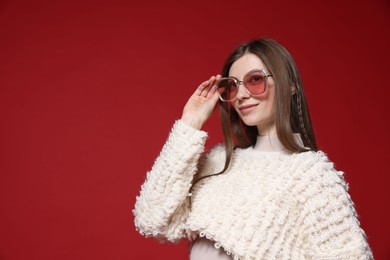 Photo of Fashionable portrait of beautiful woman in stylish outfit on red background. Space for text