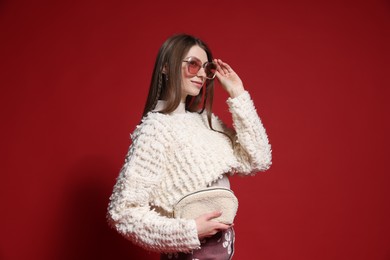 Photo of Fashionable portrait of beautiful woman in stylish outfit on red background