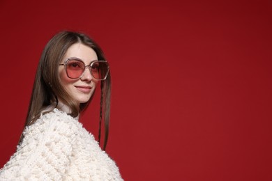 Photo of Fashionable portrait of beautiful woman in stylish outfit on red background. Space for text