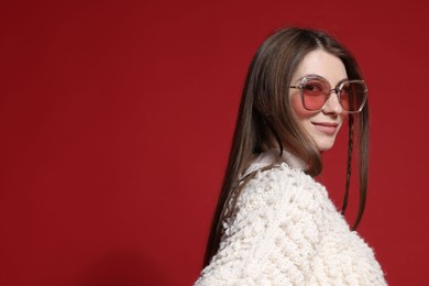 Photo of Fashionable portrait of beautiful woman in stylish outfit on red background. Space for text