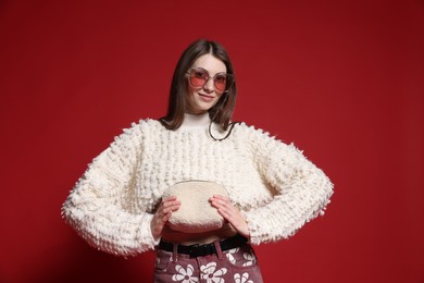 Photo of Fashionable portrait of beautiful woman in stylish outfit on red background