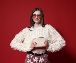 Photo of Fashionable portrait of beautiful woman in stylish outfit on red background