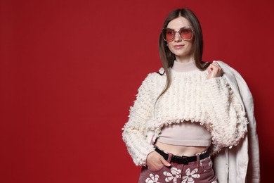 Photo of Fashionable portrait of beautiful woman in stylish outfit on red background. Space for text